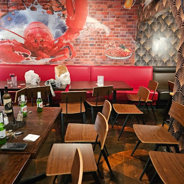 Interior of Cyndy's Seafood restaurant with a large lobster mural, red booths, and wooden tables.