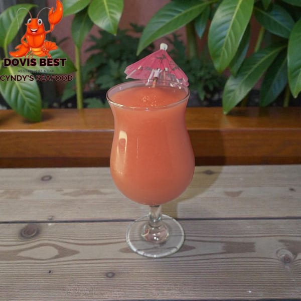 A vibrant pink frozen drink with a small pink umbrella sits on a wooden table.