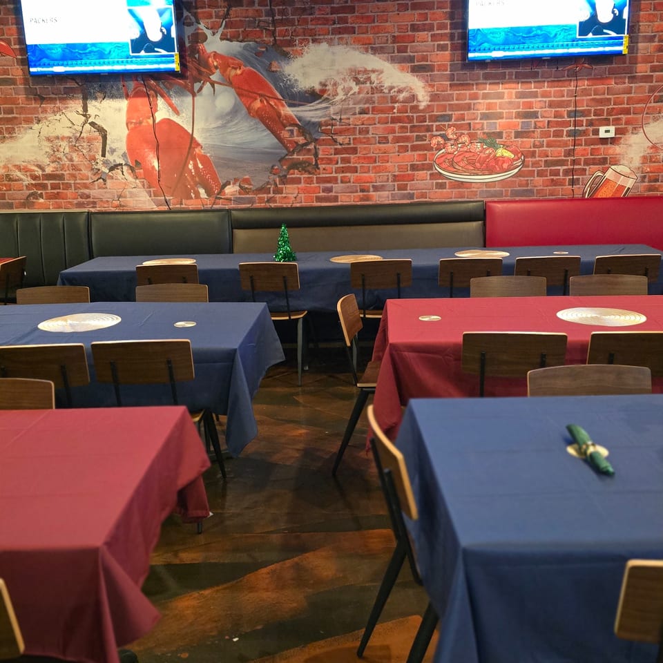 Interior of Cyndy's Seafood restaurant with blue and red tablecloths, and a brick wall mural.