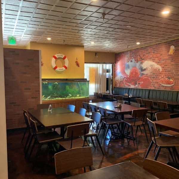 Interior of Cyndy's Seafood restaurant with tables, chairs, a large aquarium, and a lobster mural.