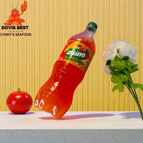 Djino fruit cocktail bottle, a red apple, and white flowers on a white surface with a yellow background.
