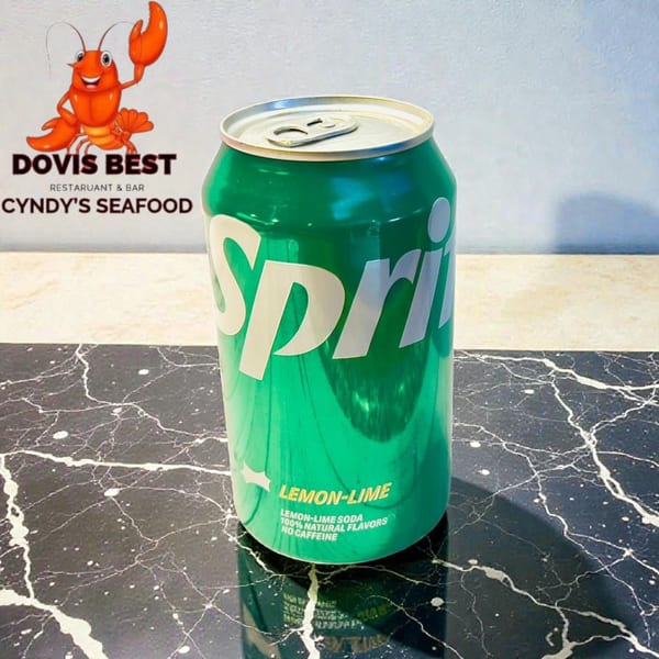 A green Sprite lemon-lime soda can stands on a black marble surface with a restaurant logo in the background.